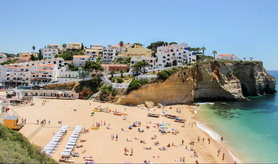 Houses and yellow sand on the shore of Algarve's Praia do Carvoeiro.