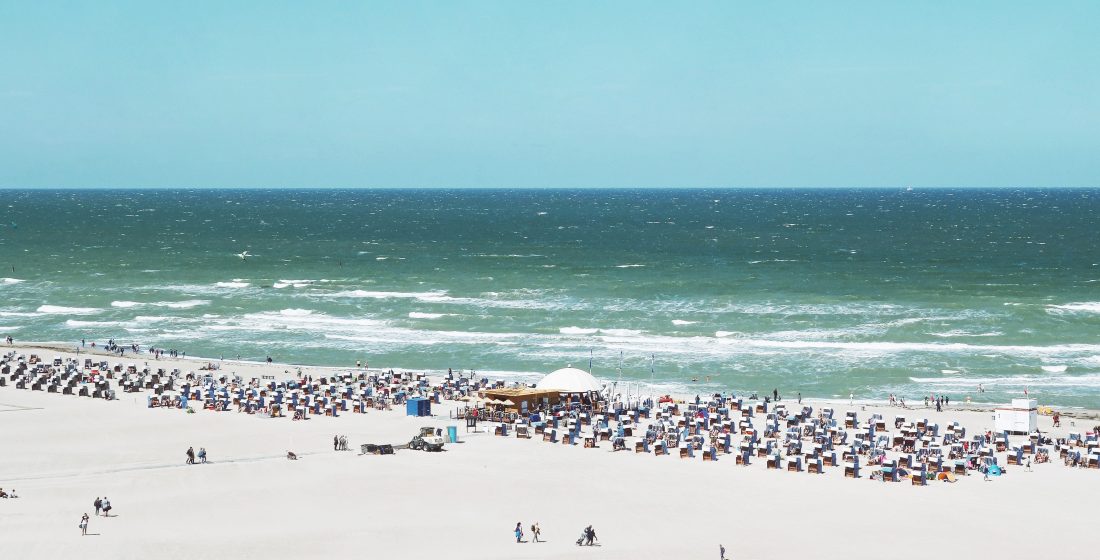 People sitting by the water at Warnemünde Beach in Germany