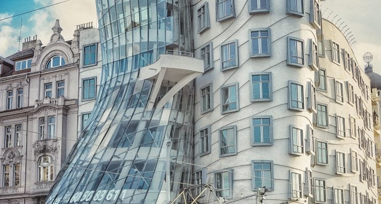 a tram passing by the dancing house in prague