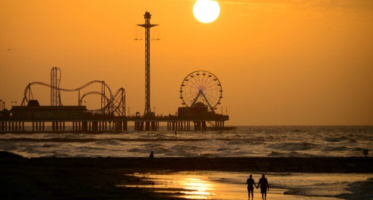 couple walking down a beach at sunset in galveston texas