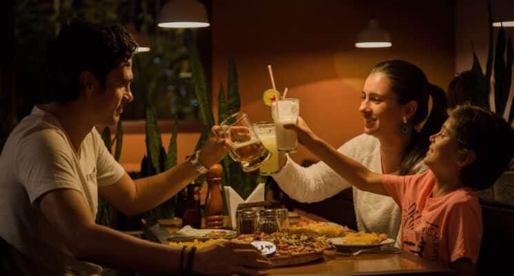 Mom, dad, and child holding up drinks in a restaurant